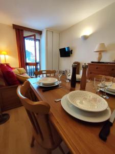 a wooden table with plates and wine glasses on it at Le Carré Coloré in Ustou