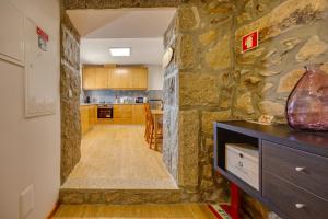 a kitchen with a large stone wall and a counter at Os Paizinhos do Arrujo in Cinfães