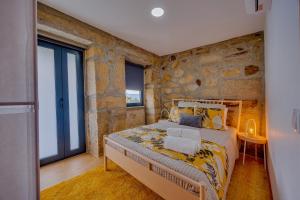 a bedroom with a bed and a stone wall at Os Paizinhos do Arrujo in Cinfães