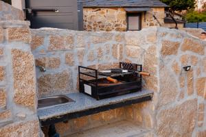 a stone wall with a grill and a sink at Os Paizinhos do Arrujo in Cinfães