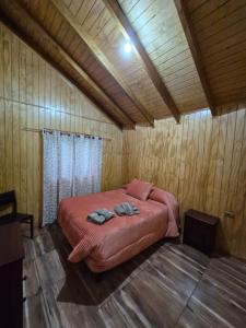 a bedroom with a bed in a wooden room at Cabaña Nuevo Amanecer in San José de la Mariquina