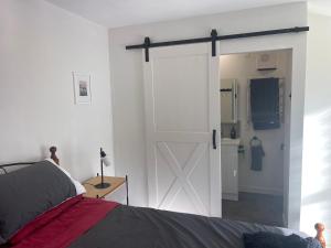 a bedroom with a sliding barn door and a kitchen at Kaiapoi Village Le Shack in Kaiapoi