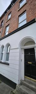 a white house with a black door and a brick building at The Roost in Derry Londonderry
