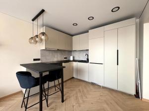a kitchen with a black table and white cabinets at Work & Stay Apartment Klaipėda in Klaipėda +2 photos