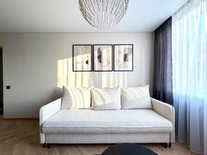 a living room with a couch and a chandelier at Work & Stay Apartment Klaipėda in Klaipėda