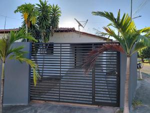 a garage with a black gate and two palm trees at Nosso Lar casa inteira, completa e independente in Barra do Garças