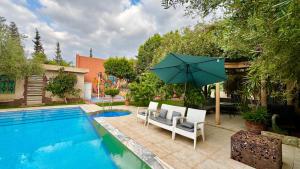 a pool with two chairs and an umbrella next to it at Villa familiale avec piscine privée sans vis à vis in Oulad Raho