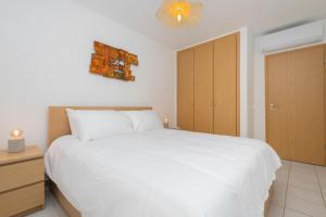 a bedroom with a white bed and a wooden cabinet at Cantinho Lusitano in Portimão +15 photos