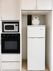 a white kitchen with a microwave and a refrigerator at Sea view panorama 62 in Haifa