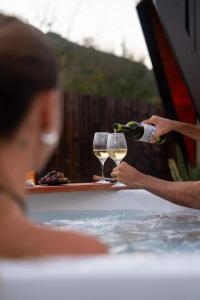 a woman holding two glasses of wine in a bathtub at La Cautiva in Lozano