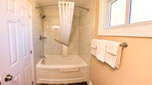 a bathroom with a sink and a shower with towels at Maple Leaf Inn & Suites in Kincardine +53 photos