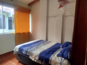 a bedroom with a bed with blue sheets and a window at Casa independiente de 2 pisos con 03 cuartos in Morales
