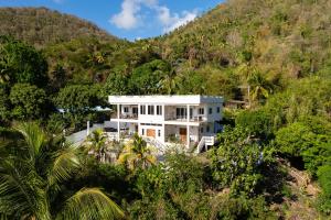 a white house in the middle of a mountain at You 4 Ric Piton Suites in Soufrière