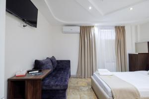 a hotel room with a bed and a couch and a tv at Time Boutique Hotel in Yerevan