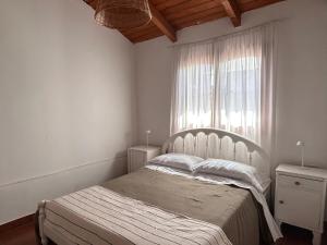 a white bedroom with a bed and a window at Cabaña Cali in Cafayate