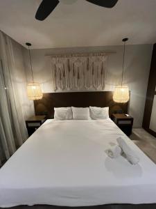 a bedroom with a large white bed with two lights at Bakal Luxury Condos in Tulum