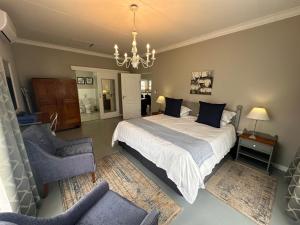 a bedroom with a bed and a chair and a chandelier at Steenkoppies semi self catering apartment in Magaliesburg +22 photos