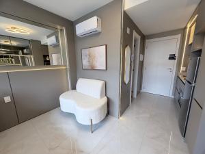 a living room with a white chair and a door at Studio 208 Premium 450m do Consulado EUA in Porto Alegre