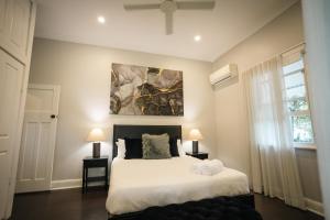a bedroom with a bed with white sheets and a painting at The Foxman Cottage in Broke
