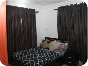 a bedroom with a bed with black curtains at Kadosh Homes - 2Bed Apartment in Magboro