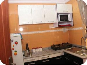 a small kitchen with a refrigerator and a microwave at Kadosh Homes - 2Bed Apartment in Magboro
