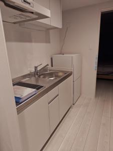 a small kitchen with a sink and a refrigerator at StadtLeben東北ゲートウエイ2新築広々仙台駅徒歩5分 in Sendai