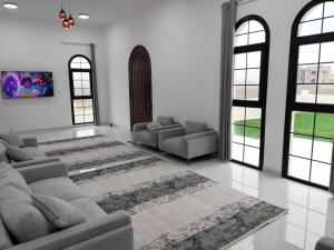 a living room with a couch and chairs and windows at رزات كاسا - للعائلات فقط in Gharnūt