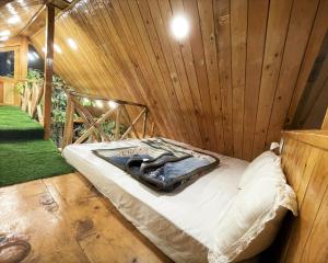 a room with a bed in a wooden wall at Himalayan Abode Tree House in Sainj