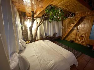 a bedroom with a white bed and a tree at Himalayan Abode Tree House in Sainj