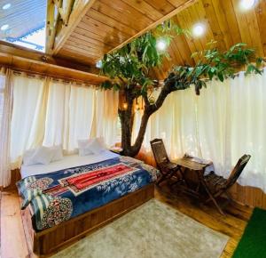 a bedroom with a bed and a tree in it at Himalayan Abode Tree House in Sainj
