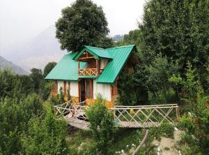a house with a green roof on a hill at Himalayan Abode Tree House in Sainj +30 photos
