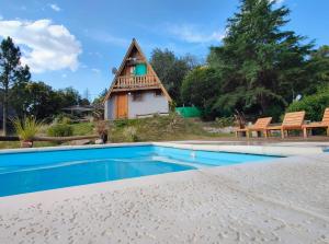 a thatched house with a pool in front of it at Cabañas Damel in Villa Giardino