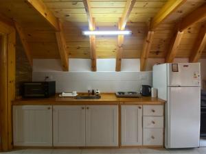 a kitchen with a white refrigerator and wooden ceilings at Cabañas Damel in Villa Giardino
