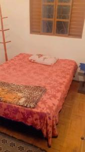 a bed with a red comforter and a pillow on it at Pousada May in Ribeirão Preto
