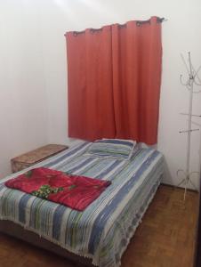 a bed in a room with a red curtain at Pousada May in Ribeirão Preto