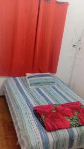 a bed in a room with a red curtain at Pousada May in Ribeirão Preto +4 photos