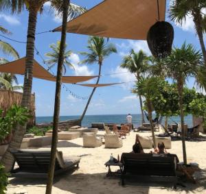 two people sitting on the beach under an umbrella at Private Pool with Beach Access and Baby Crib - Tulum Hotel Zone in Tulum