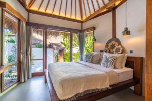 a bedroom with a large bed and large windows at MELO Gili Air in Gili Islands