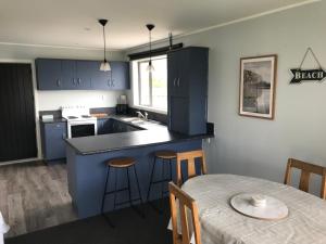 a kitchen with blue cabinets and a table with a tableablish at Cosy Beach House in Riverton