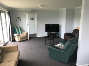 a living room with a couch and a television at Cosy Beach House in Riverton