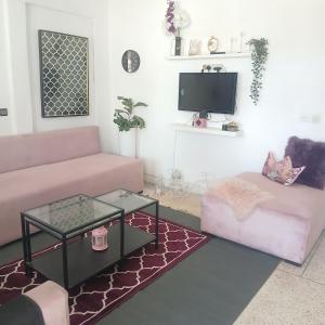 a living room with a pink couch and a coffee table at Sultana in Ech Chorfa