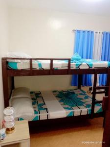 two bunk beds in a room with blue curtains at 3 J'S Homestay in Carles +3 photos