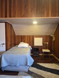 a bedroom with a bed and a table and a chair at Alojamientos La Casita del Centro in Panguipulli
