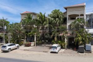 two cars parked in front of a building with palm trees at Tama Magico in Tamarindo