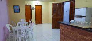 a kitchen with white chairs and a counter with a refrigerator at Recanto Life Beach in Camocim