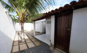 a palm tree next to a building with a door at Recanto Life Beach in Camocim