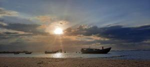 a group of boats on a beach with the sun shining at Recanto Life Beach in Camocim