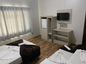 a hotel room with two beds and a television at Hotel Panorâmico in Penha
