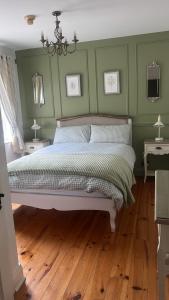 a bedroom with a bed with green walls and wooden floors at The Lodge Self Catering Donegal Town in Donegal