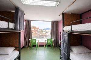 a room with bunk beds and a table and chairs at J Cafe & Hostel in Chiang Mai